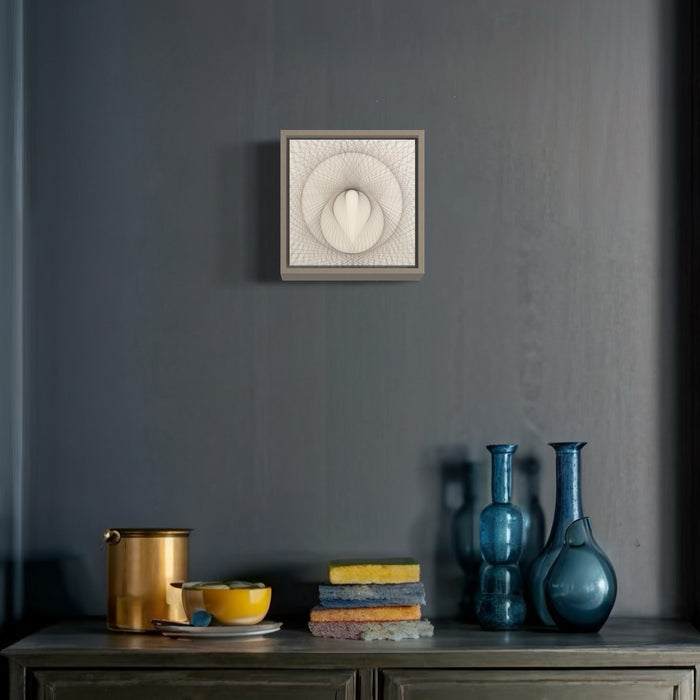 The artwork 'Empty Void 28' by Jayoung Yoon features a mesmerizing circular pattern created with human hair and acrylic medium on an 8x8 panel, displayed above a styled vignette with blue glass vessels, brass containers, and colorful textiles. The piece showcases intricate radial designs in white against a neutral background, framed in a minimalist grey frame. Art by Jayoung Yoon.